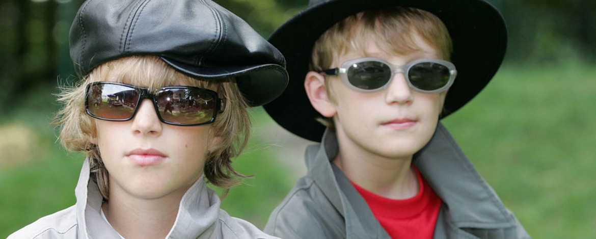 Zwei als Agenten verkleidete Kinder, die Hüte, Mäntel und dunkle Brillen tragen.